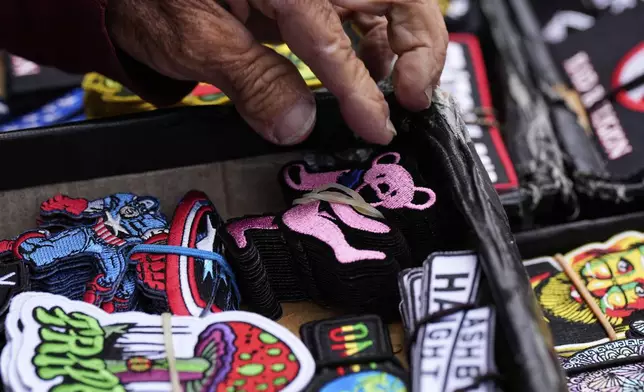 A merchant picks up a Grateful Dead patch out his inventory for a customer in San Francisco, Saturday, July 19, 2025. (AP Photo/Godofredo A. Vásquez)