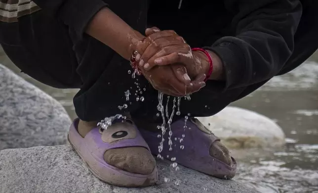 A woman washes her hands in a river at the newly relocated settlement of the abandoned Samjung village in the Mustang region, 462 kilometers (288 miles) west of Kathmandu, Nepal, Friday, April 18, 2025. (AP Photo/Niranjan Shrestha)