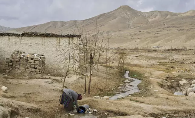 A woman collects water at the newly relocated settlement of the abandoned Samjung village in the Mustang region, 462 kilometers (288 miles) west of Kathmandu, Nepal, Saturday, April 19, 2025. (AP Photo/Niranjan Shrestha)