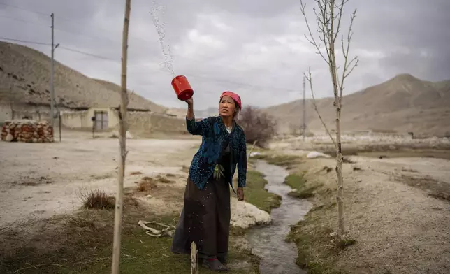 Tashi Angmo, 41, performs her morning prayers with water before collecting it for daily use at the newly relocated settlement of the abandoned Samjung village in the Mustang region, 462 kilometers (288 miles) west of Kathmandu, Nepal, Saturday, April 19, 2025. (AP Photo/Niranjan Shrestha)
