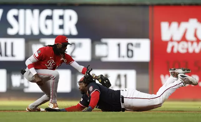 Washington Nationals' Josh Bell, right, avoids a tag by Cincinnati Reds shortstop Elly De La Cruz, left, and slides into second base on a double hit off pitcher Brady Singer during the first inning of a baseball game in Washington, Monday, July 21, 2025. (AP Photo/Terrance Williams)