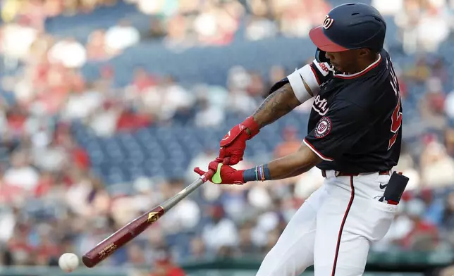Washington Nationals' Daylen Lile hits a triple off Cincinnati Reds pitcher Brady Singer which scored James Wood, Josh Bell and Nathaniel Lowe during the first inning of a baseball game in Washington, Monday, July 21, 2025. (AP Photo/Terrance Williams)