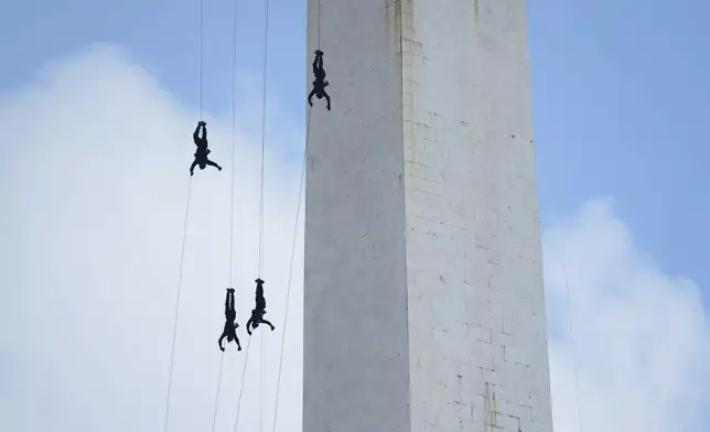 Paramilitary police unit Mobile Brigade (Brimob) members rappel down the National Monument during a show marking the 79th anniversary of the Indonesian National Police in Jakarta, Indonesia, Tuesday, July 1, 2025. (AP Photo/Tatan Syuflana)