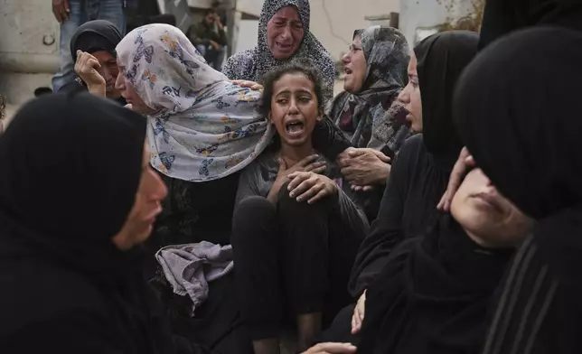 Lian Al-Za'anin, center, is comforted by relatives as she mourns the loss of her father, Rami Al-Za'anin, who was killed while heading to an aid distribution hub, at the morgue of the Shifa Hospital in Gaza City, on Thursday, July 3, 2025. (AP Photo/Jehad Alshrafi)