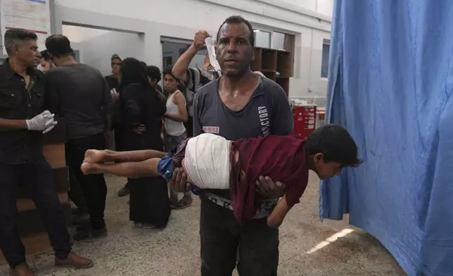 A man carries a child, who was wounded in an Israeli strike, after being treated in the Shifa Hospital, Gaza City, Monday, June 30, 2025. (AP Photo/Jehad Alshrafi)