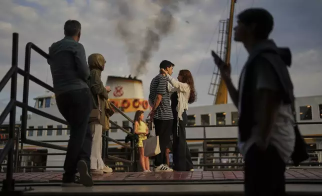 A couple and other passengers wait to board a ferry at the Besiktas terminal on the European side of Istanbul, Turkey, Thursday, May 22, 2025. (AP Photo/Francisco Seco)