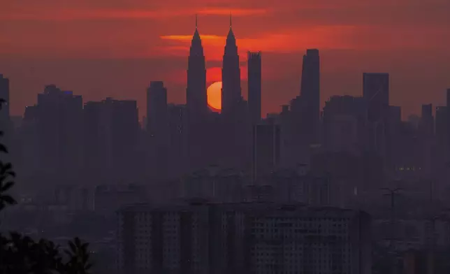 The sun sets behind the city center in Kuala Lumpur, Malaysia, Monday, June 30, 2025. (AP Photo/Vincent Thian)