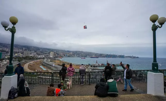 People stand at Baron viewpoint, high above the sea, to watch the water after a precautionary tsunami warning in Valparaiso, Chile, Wednesday, July 30, 2025, after an earthquake struck off the coast of Russia. (AP Photo/Esteban Felix)