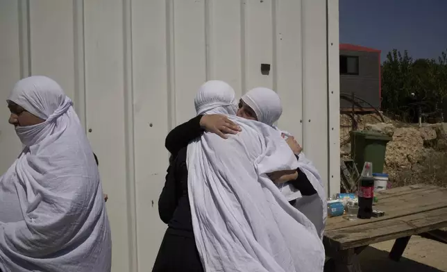 Druze women from Syria and Israel bid farewell before the Syrians cross back into Syria at the Israeli-Syrian border, in the Israeli-controlled Golan Heights town of Majdal Shams, Thursday, July 17, 2025. (AP Photo/Leo Correa)