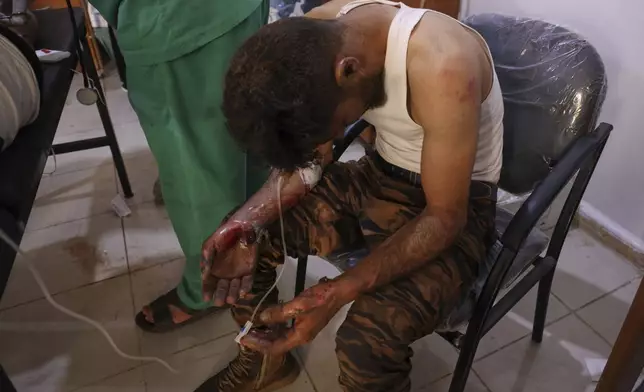 A Syrian government soldier who was injured in Sweida city during clashes between the government troops and Druze militias, waits for treatment at a clinic in Busra al-Harir village, southern Syria, Tuesday, July 15, 2025. (AP Photo/Omar Albam)