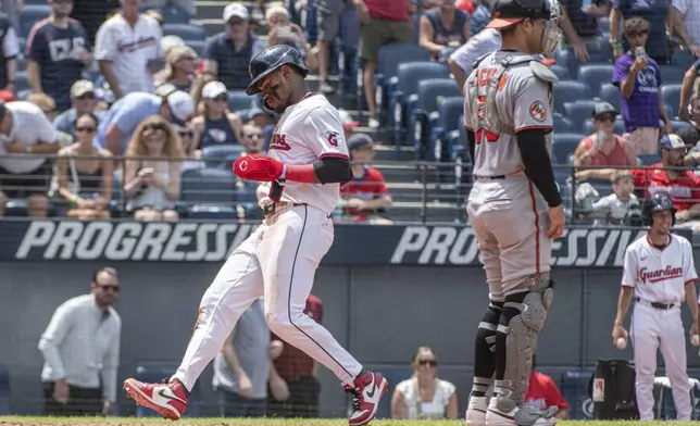 Cleveland Guardians' Angel Martinez, left, scores on a sacrifice fly by Nolan Jones as Baltimore Orioles' Alex Jackson looks towards the field during the third inning of a baseball game, Thursday, July 24, 2025, in Cleveland. (AP Photo/Phil Long)