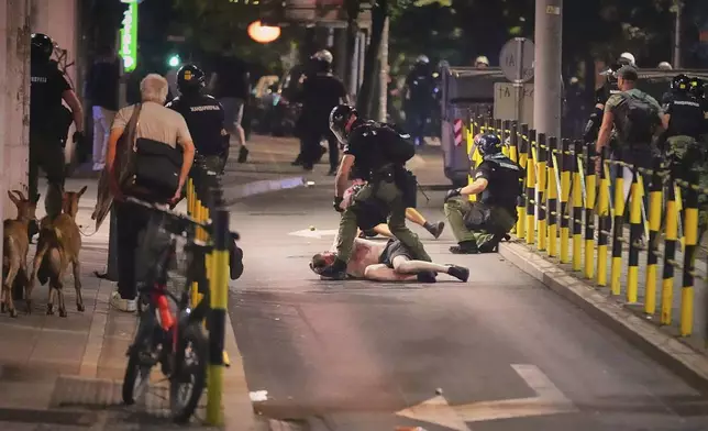 A man walks with two goats as riot police detain a man after charging protesters at the end of an anti-government rally pressing for an early election after nearly eight months of almost daily anti-corruption demonstrations that have shaken the populist government of President Aleksandar Vucic, in Belgrade, Serbia, Saturday, June 28, 2025. (AP Photo/Darko Vojinovic)