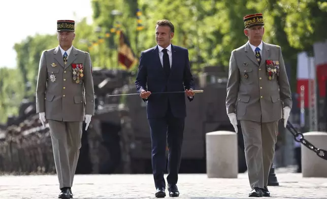 French President Emmanuel Macron holds a new sword during a cermony with Chief of Staff of the French Armed Forces Thierry Burkhard, left, and and Military Governor of Paris Loic Mizon during the Bastille Day military parade in Paris, Monday, July 14, 2025. (Abdul Saboor/Pool via AP)