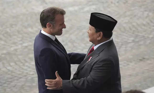 French President Emmanuel Macron welcomes Indonesia's President Prabowo Subianto during the Bastille Day parade, Monday, July 14, 2025 in Paris. (AP Photo/Christophe Ena)