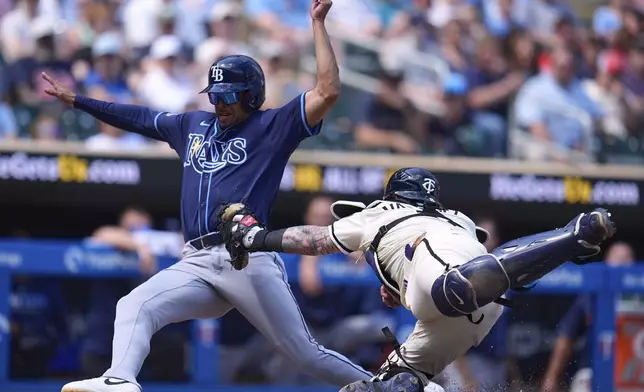 Tampa Bay Rays' Christopher Morel, left, scores as Minnesota Twins catcher Christian Vázquez, right, attempts to tag him during the eighth inning of a baseball game Sunday, July 6, 2025, in Minneapolis. (AP Photo/Abbie Parr)