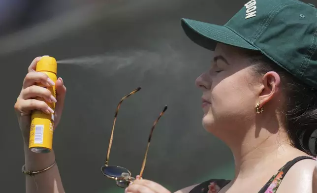 A spectator tries to keep cool on day two at the Wimbledon Tennis Championships in London, Tuesday, July 1, 2025. (AP Photo/Kin Cheung)