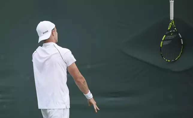 Jesper de Jong of the Netherlands reacts by tossing his racket against the fence as he plays Christopher Eubanks of the U.S. during their first round men's singles match at the Wimbledon Tennis Championships in London, Tuesday, July 1, 2025. (AP Photo/Alastair Grant)