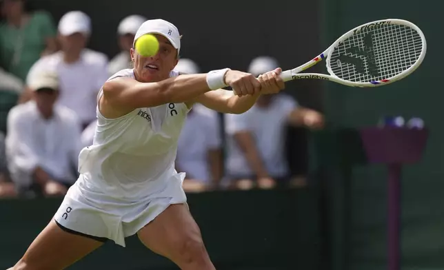 Iga Swiatek of Poland returns the ball to Polina Kudermetova of Russia during their first round women's single match at the Wimbledon Tennis Championships in London, Tuesday, July 1, 2025.(AP Photo/Joanna Chan)