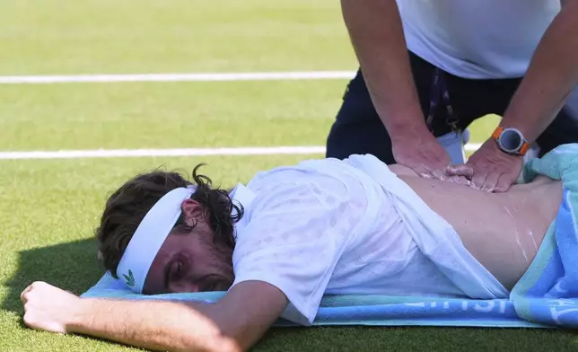 Stefanos Tsitsipas of Greece receives treatment during his first round men's single match against Valentine Royer of France at the Wimbledon Tennis Championships in London, Monday, June 30, 2025. (AP Photo/Kirsty Wigglesworth)