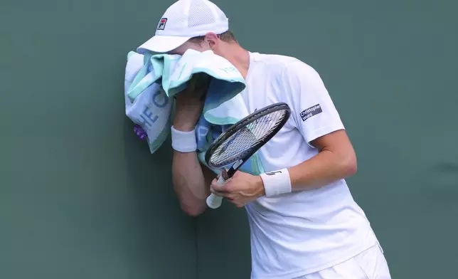 Elmar Moller of Denmark wipes his face with a towel during his match against Frances Tiafoe of the U.S. at their first round men's single match at the Wimbledon Tennis Championships in London, Monday, June 30, 2025. (AP Photo/Kirsty Wigglesworth)