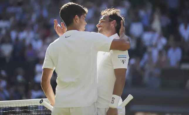 Carlos Alcaraz of Spain, left, greets Fabio Fognini of Italy at the net after winning their first round men's singles match at the Wimbledon Tennis Championships in London, Monday, June 30, 2025. (AP Photo/Alastair Grant)