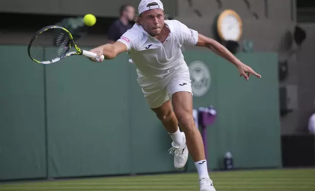 Alexandre Muller of France stretches to return to Novak Djokovic of Serbia during their first round men's singles match at the Wimbledon Tennis Championships in London, Tuesday, July 1, 2025. (AP Photo/Kin Cheung)