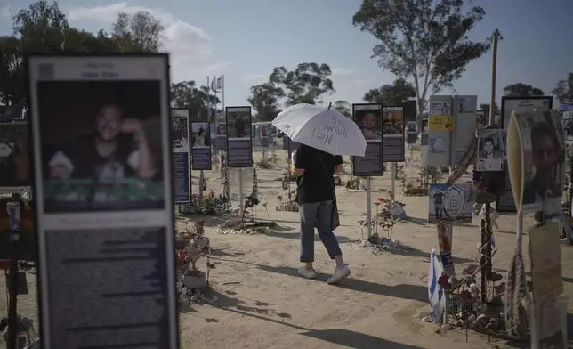 A woman walks with an umbrella reading 'End the war immediately,' during a protest demanding immediate release of hostages held by Hamas in the Gaza Strip, at the site of the October 7, 2023, Hamas attack on the Nova music festival near Kibbutz Re'im in southern Israel, Wednesday, July 2, 2025. (AP Photo/Ohad Zwigenberg)