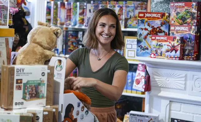 Hilary Key, owner of The Toy Chest, straightens merchandise on the shelves of her toy store in Nashville, Ind., Thursday, June 26, 2025. (AP Photo/Michael Conroy)