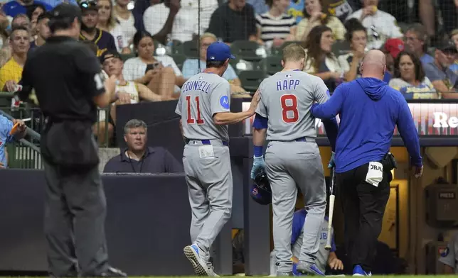 Chicago Cubs' Ian Happ (8) is helped off the field by a trainer and manager Craig Counsell (11) after suffering an injury during the eighth inning of a baseball game against the Milwaukee Brewers, Tuesday, July 29, 2025, in Milwaukee. (AP Photo/Aaron Gash)