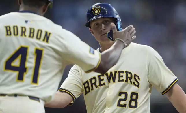 Milwaukee Brewers' Andrew Vaughn (28) is congratulated by first base coach Julio Borbon (41) after hitting an RBI single during the fifth inning of a baseball game against the Chicago Cubs, Tuesday, July 29, 2025, in Milwaukee. (AP Photo/Aaron Gash)