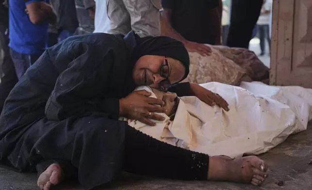 Khaleda El-Feki embraces the body of her husband, Mohamed El-Maghribi, who was killed in an Israeli airstrike, at Al-Aqsa Hospital in Deir al-Balah, central Gaza Strip, Thursday, July 24, 2025. (AP Photo/Abdel Kareem Hana)