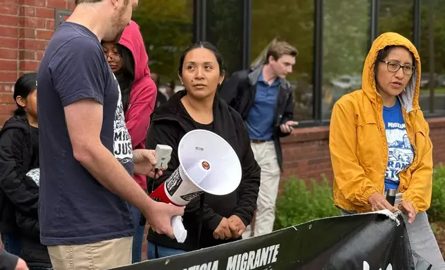 Wuendy Bernardo, foreground center, a migrant dairy farmworker at risk of deportation, is greeted by Migrant Justice staff member Will Lambek, left, outside a U.S. Immigration and Customs Enforcement office in St. Albans, Vt., on Friday, June 20, 2025. Lambek led a rally in support of Bernardo as she reported to the office for an appointment. (AP Photo/Amanda Swinhart)