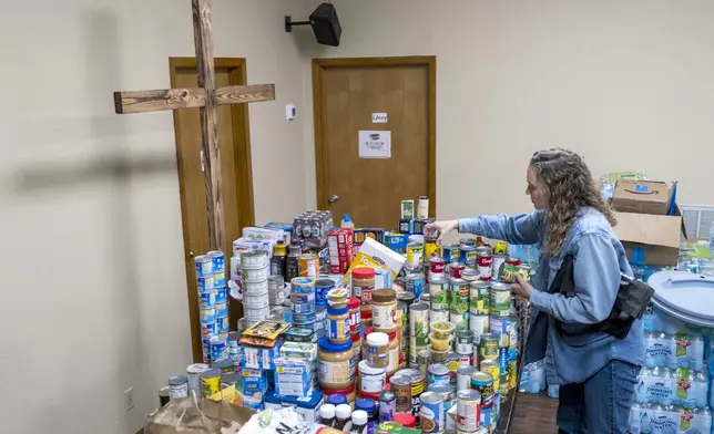 Parishioner Lisa Reitz gets cans of food and other donations ready for distribution at the Hunt Baptist Church following extreme flooding along the Guadalupe River on Sunday, July 6, 2025, in Hunt, Texas. (AP Photo/Rodolfo Gonzalez)