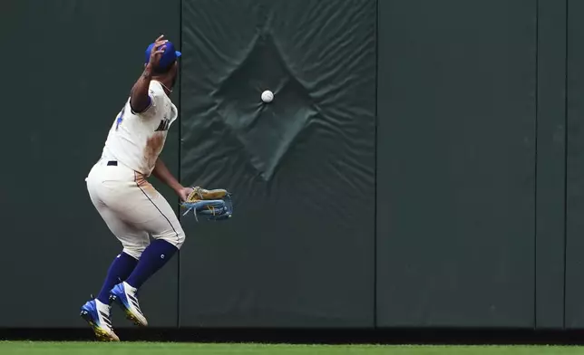 The two-run double ball from Houston Astros' Taylor Trammell makes a pattern as it bounces off the outfield wall as Seattle Mariners center fielder Julio Rodriguez looks on during the seventh inning of a baseball game Sunday, July 20, 2025, in Seattle. (AP Photo/Lindsey Wasson)