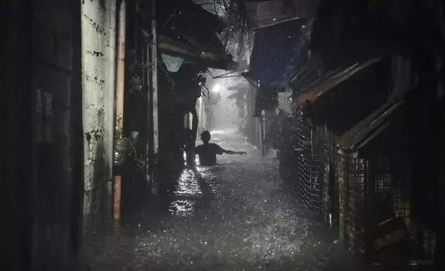 A man wades along waist-deep floods at a residential area after Tropical Storm Wipha caused intensified monsoon rains that bought flooding in Quezon city, Philippines, on Monday, July 21, 2025. (AP Photo/Aaron Favila)