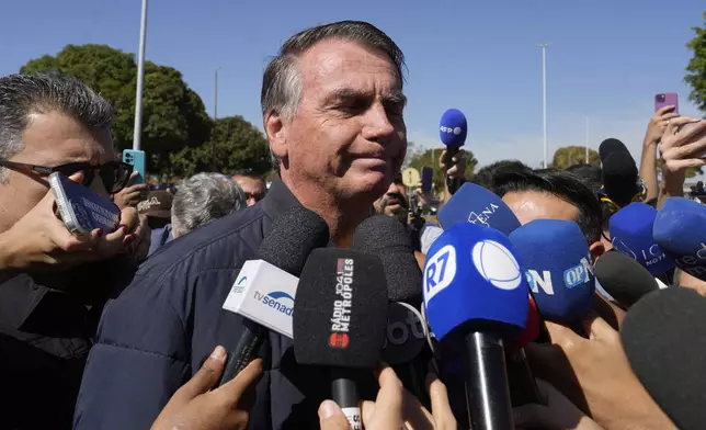 Brazil's former President Jair Bolsonaro speaks to the press outside the Secretariat of Penitentiary Administration where he arrived after the Supreme Court ordered him to be fitted with an electronic ankle monitor in Brasilia, Brazil, Friday, July 18, 2025. (AP Photo/Eraldo Peres)