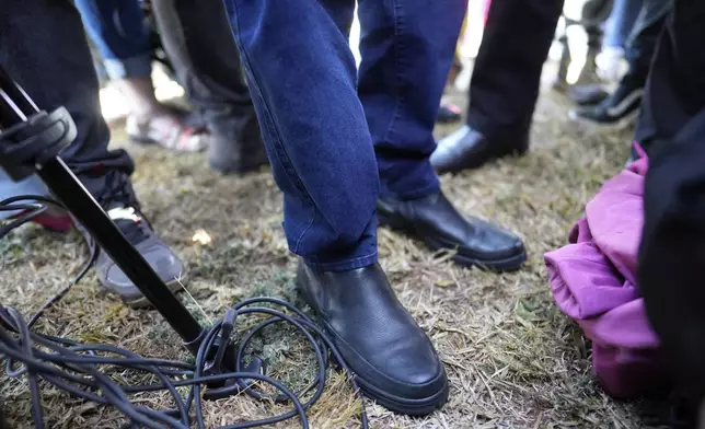 The feet of Brazil's former President Jair Bolsonaro are photographed as he stops to speak with the press while leaving the Secretariat of Penitentiary Administration after the Supreme Court ordered him to be fitted with an electronic ankle monitor in Brasilia, Brazil, Friday, July 18, 2025. (AP Photo/Eraldo Peres)