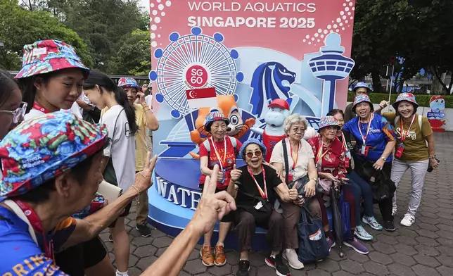 Elderly visitors pose for photos with the World Aquatics sign in Singapore, Wednesday, July 23, 2025. (AP Photo/Ng Han Guan)