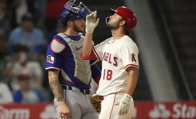 Los Angeles Angels' Nolan Schanuel, right, gestures after hitting a two-run home run as Texas Rangers catcher Jonah Heim stands by during the eighth inning of a baseball game Wednesday, July 30, 2025, in Anaheim, Calif. (AP Photo/Mark J. Terrill)