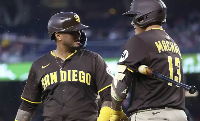 San Diego Padres' Jose Iglesias celebrates with San Diego Padres' Manny Machado after scoring a run during the third inning of a baseball game against the Washington Nationals, Saturday, July 19, 2025, in Washington. (AP Photo/Daniel Kucin Jr.)