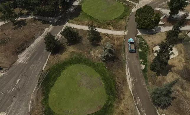 A dump truck exits a temporary recycling facility set up on a golf course in Altadena, Calif., Wednesday, June 4, 2025, after unloading debris removed from wildfires. (AP Photo/Jae C. Hong)