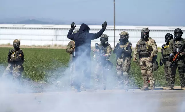 FILE - Federal immigration agents toss tear gas at protesters during a raid in the agriculture area of Camarillo, Calif., Thursday, July 10, 2025. (AP Photo/Michael Owen Baker, File)