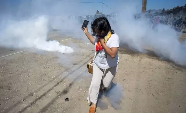 FILE - A protester runs from tear gas tossed by federal immigration agents to clear a path for the vehicles during a raid in the agriculture area of Camarillo, Calif., Thursday, July 10, 2025. (AP Photo/Michael Owen Baker, File)