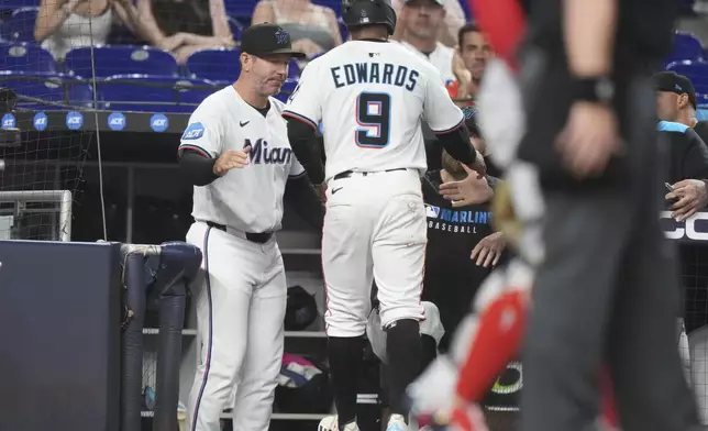 Miami Marlins' Xavier Edwards (9) is met by manager Clayton McCullough, left, after scoring on a single hit by Jesus Sanchez during the third inning of a baseball game against the Minnesota Twins, Thursday, July 3, 2025, in Miami. (AP Photo/Lynne Sladky)