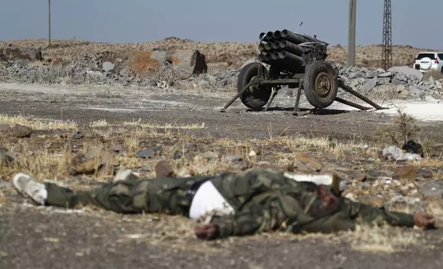 A dead fighter of the Druze militias lies on the ground in front of a rocket launcher on the outskirts of Sweida city, where clashes erupted between Sunni Bedouin clans and Druze militias, southern Syria, Monday, July 14, 2025. (AP Photo/Omar Sanadiki)