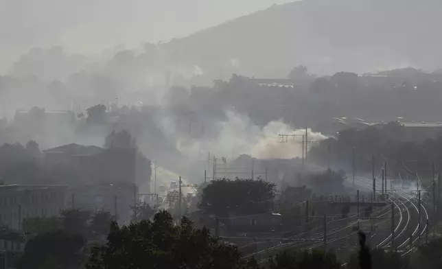 Smoke is seen by rail tracks during a wildfire Tuesday, July 8, 2025 in Marseille, southern France. (AP Photo/Lewis Joly)