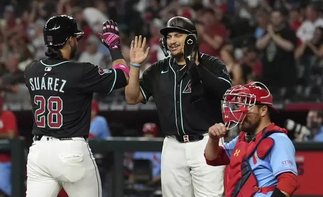 Arizona Diamondbacks' Eugenio Suárez (28) celebrates his two-run home run against the St. Louis Cardinals with Diamondbacks' Josh Naylor, center, as St. Louis Cardinals catcher Pedro Pagés, right, pauses at home plate during the first inning of a baseball game Saturday, July 19, 2025, in Phoenix. (AP Photo/Ross D. Franklin)