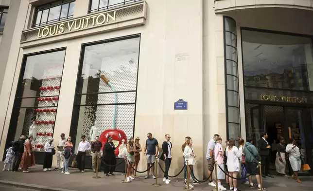 People queue outside the Louis Vuitton store, Monday, July 28, 2025 in Paris. (AP Photo/Thomas Padilla)