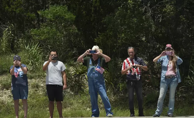 People watch as President Donald Trump and first lady Melania Trump pass in a motorcade in Kerrville, Texas, to monitor flood damage, Friday, July 11, 2025. (AP Photo/Jacquelyn Martin)