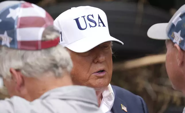 President Donald Trump, center, greets first responders as he observes flood damage in Kerrville, Texas, Friday, July 11, 2025. (AP Photo/Jacquelyn Martin)